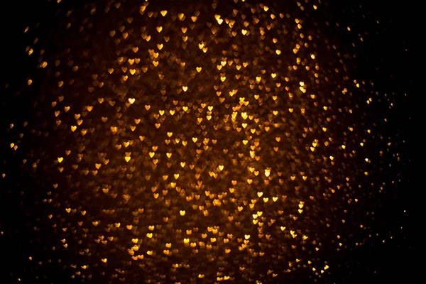 Fundo escuro com bokeh dourado na forma de um coração . — Fotografia de Stock