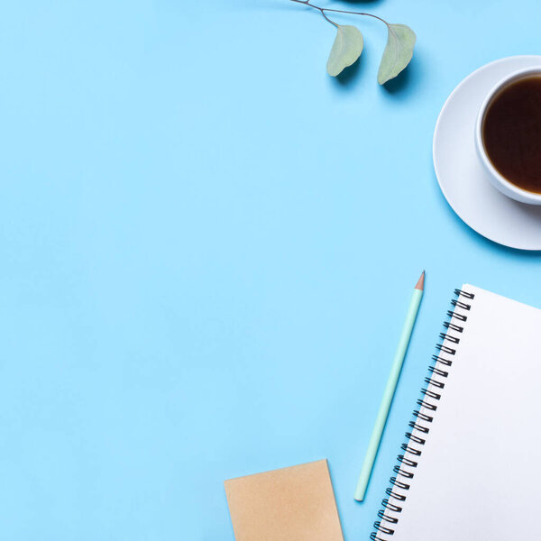 Blue background with notepad, pencil and cup of coffee.