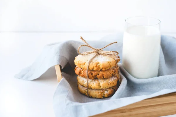 Biscoitos empilhados em um guardanapo de linho e um copo de leite . — Fotografia de Stock