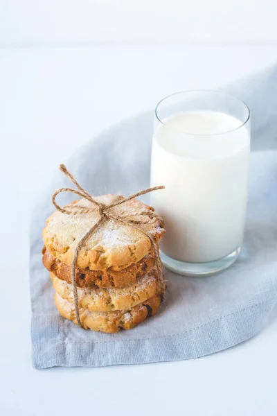 Biscoitos empilhados em um guardanapo de linho e um copo de leite . — Fotografia de Stock