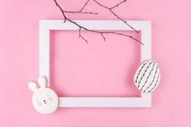 Pembe arka planda Paskalya yumurtası ve tavşan kurabiyesi..