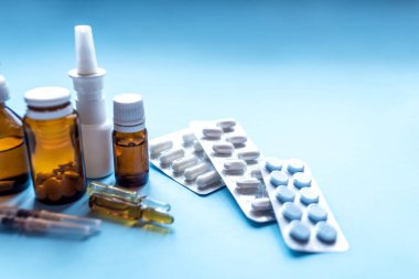 Tabletler, mavi arka planda ilaç şişeleri olan bir paket ilaç..