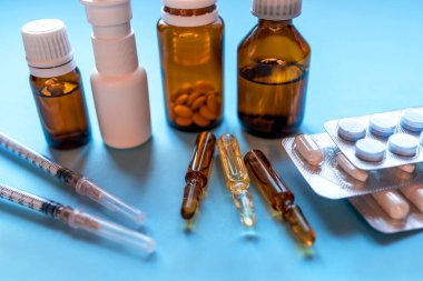 Tabletler, mavi arka planda ilaç şişeleri olan bir paket ilaç..