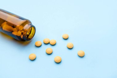 İlaç hapları ve mavi arka planda şişe..