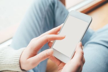 Beyaz ekranlı telefonu tutan kadın elleri.