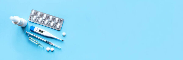 Digital thermometer and medicaments on blue background.
