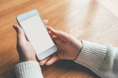 Beyaz ekranlı telefonu tutan kadın elleri.