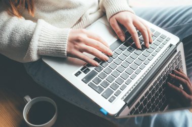 Evde dizüstü bilgisayarıyla çalışan genç bir kadın..