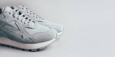 Gri arka planda gri spor ayakkabılar.