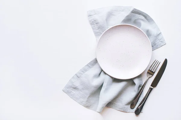 Um prato vazio e talheres em uma mesa branca. — Fotografia de Stock