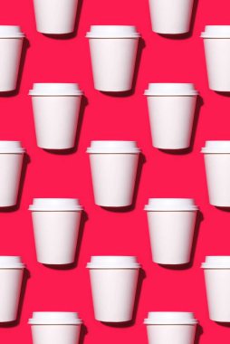 Kırmızı arka planda tek kullanımlık kahve fincanları..