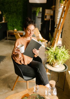 Kafede otururken dizüstü bilgisayarla iş yapan genç bir kadının portresi..