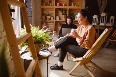 Çekici bir adam ve çekici bir kadın dizüstü bilgisayarı işaret ediyor. Kafede bir fincan kahveyle çalışıyor ve dinleniyor..