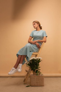 Mavi elbiseli kız stüdyo arka planında çiçekler, tüm vücut ve portre, bahar, moda fotoğrafı. Cazibeli bayan