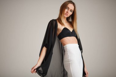 Çizgili pantolon ve siyah bluzlu moda kızı stüdyo arka planında, süpermodel pozu, fotokopi alanı