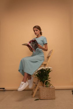 Mavi elbiseli kız stüdyo arka planında çiçekler, tüm vücut ve portre, bahar, moda fotoğrafı. Cazibeli bayan