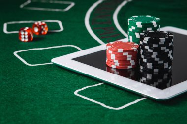 Poker ve kumar konsepti. Poker fişleri ve yeşil bir keçenin üzerindeki dijital masa.