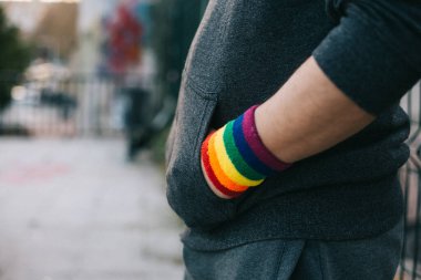 Elleri cebinde eşcinsel bileziği olan bir çocuğun yan görüntüsü sokakta duruyor.