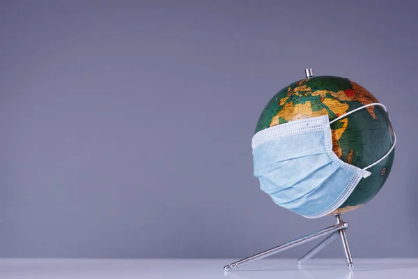 Isolated earth globe with face mask protection with space for text. Traveling worldwide and coronavirus medical concept.