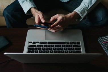 Çalışırken telefon kullanan genç bir girişimcinin ellerini kapat.