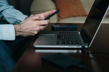 Evden çalışırken akıllı telefon kullanan bir adamın ellerini kapat.