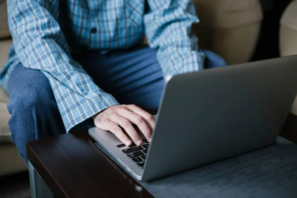 Man in pajamas sitting on the couch is working remotely from home. Businessman in quarantine for coronavirus