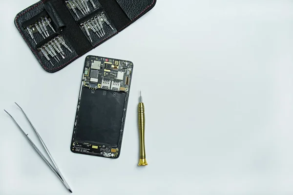 Reparación de teléfonos inteligentes. Smartphone desmontado, destornilladores para desmontar el teléfono. Asiento plano, vista superior. Fondo blanco. Espacio para texto . — Foto de Stock