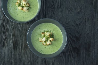 Kremalı ıspanak çorbası, kraker, bitki ve chia tohumları. Ahşap bir masada bir kasede servis edilen yeşil çorba. Düz yatıyordu.