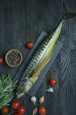 Tütsülenmiş uskumru. Kesme tahtasında soğuk füme uskumru. Koyu ahşap arka plan. Yukarıdan görüntüle.