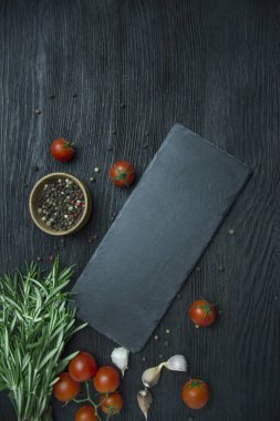 Yemek yapmak için baharat ve otlar. Yemek pişirme konsepti şablonu. Biberiye, bezelye, vişne, siyah arka planda tahta. Kopyalama alanı olan üst görünüm. Düz yatıyordu