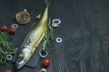 Tütsülenmiş uskumru. Kesme tahtasında soğuk füme uskumru. Koyu ahşap arka plan. Yukarıdan bak. Metin için boşluk.