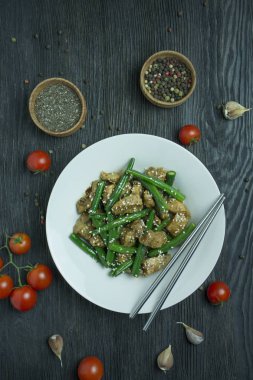 İçinde susam tohumları serpiştirilmiş yeşil fasulye ve et salatası. Yeşil fasulyeli sıcak salata servisi. Kuşkonmazlı salata. Asya yemekleri. Koyu tahta arkaplan.