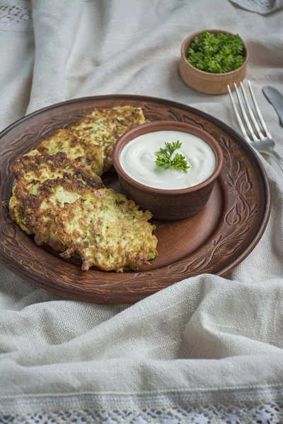 Frittelle di zucchine. Crepes vegetariane di zucchine servite con erbe fresche e panna acida. Sfondo chiaro . — Foto Stock