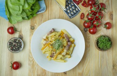 Peynirli İtalyan makarnası, balkabağı ve kızarmış domuz pastırması, beyaz tabakta servis ediliyor. Hafif ahşap zemin. Metin için boşluk.