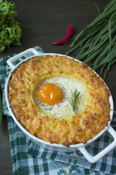 Potato casserole with bolognese. Baked potato casserole with egg and grated cheese in a ceramic oval baking sheet. Wooden dark background. — Stock Photo, Image