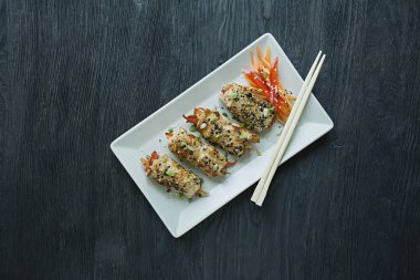 Yeşil, havuç dilimleri, karanlık bir kesme tahtasında biber ile taze tavuk göğsü ile Rolls. Sağlıklı ev yapımı gıda kavramı. Koyu ahşap arka plan.