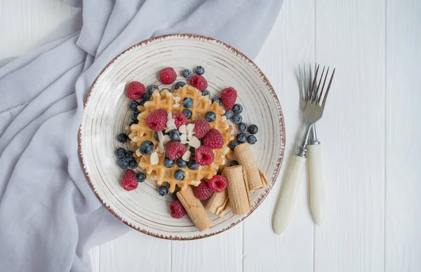 Waffles with fresh raspberries, blueberries for breakfast. Belgian waffles. Light wooden background. — Stock Photo, Image
