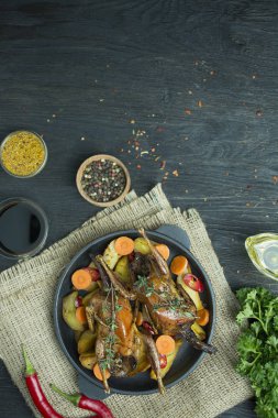 Tavada sebzeli fırında bıldırcın. Mesaj için yer var. Koyu arkaplan.