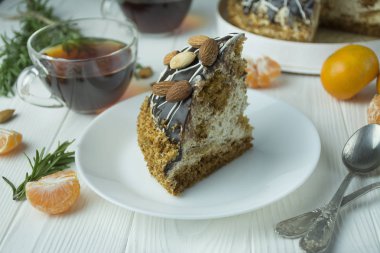 Açık ahşap zemin üzerinde beyaz bir tabakta bademli çikolatalı pasta. Pastalı çay partisi. Yemek masası..