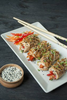 Fırında tavuk göğsü ruloları, otlar, havuç dilimleri, kesme tahtasında dolmalık biber. Sağlıklı beslenme dengesi. Yemek pişirmek. Koyu tahta arkaplan.