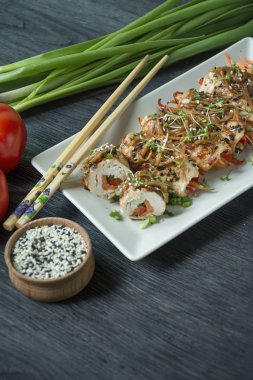 Fırında tavuk göğsü ruloları, otlar, havuç dilimleri, kesme tahtasında dolmalık biber. Asya tarzı. Sağlıklı beslenme dengesi. Yemek pişirmek. Koyu tahta arkaplan.