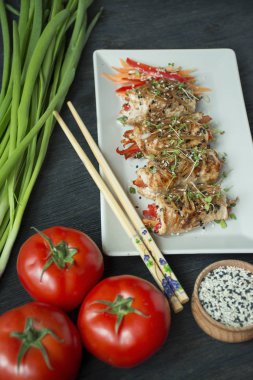 Fırında tavuk göğsü ruloları, otlar, havuç dilimleri, kesme tahtasında dolmalık biber. Sağlıklı beslenme dengesi. Yemek pişirmek. Koyu tahta arkaplan.