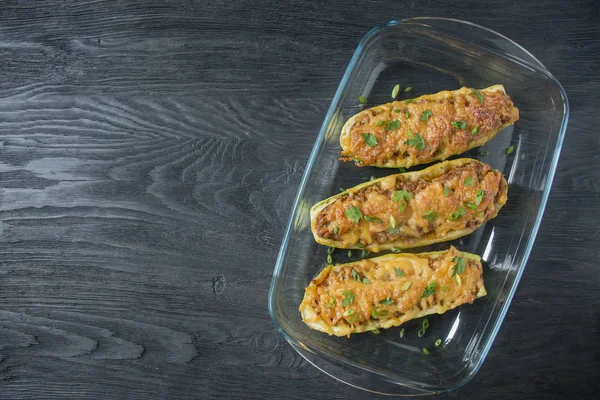 Zucchine ripiene con carne macinata e formaggio grattugiato in una teglia di vetro. Sfondo in legno scuro.Sano equilibrio alimentare.Cucina alimentare . — Foto Stock