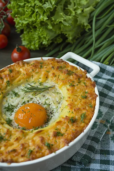 Potato casserole with bolognese. Baked potato casserole with egg and grated cheese in a ceramic oval baking sheet. Wooden dark background. — Stock Photo, Image