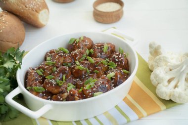 Soslu ve susamlı kızarmış Karnabahar. Asya usulü yemek. Beyaz ahşap arka plan. Mesaj için yer var. Düz yatıyordu.