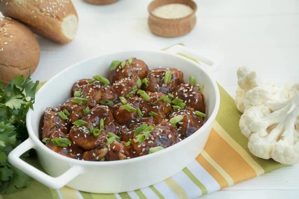 Soslu ve susamlı kızarmış Karnabahar. Asya usulü yemek. Beyaz ahşap arka plan. Mesaj için yer var. Düz yatıyordu.