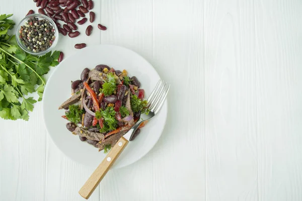 Rindfleischsalat mit Bohnen, Paprika. Salat "Tiflis", traditionelle georgische Küche. heller hölzerner Hintergrund. gesunde Balance-Ernährung. — Stockfoto