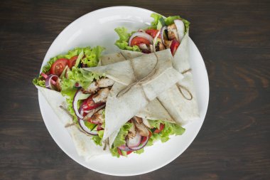 Meksika yemeği. Ahşap bir arka plan üzerinde tavuk ve sebze yakın çekim ile sarılmış burrito. Metin için alan.