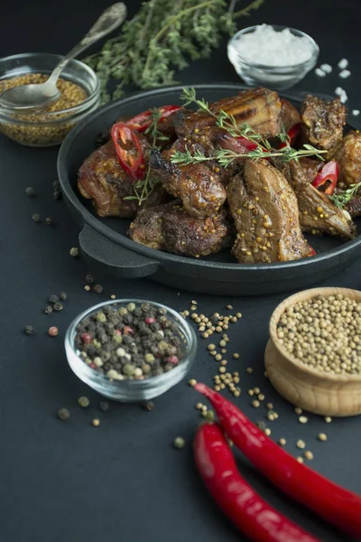 Baked ribs in a grill pan. Grilled pork ribs with spices and fresh herbs. Dark background. Space for text. Table background menu. — 스톡 사진