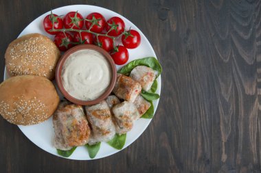 Et ve sebzeli börek kesme tahtasında servis ediliyor. Asya yemekleri. Pirinç kağıdı. Koyu renk ahşap